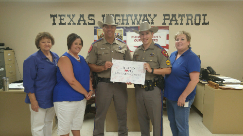 Image of three women and two police officers holding a sign saying, "Legend Loves Law Enforcement".